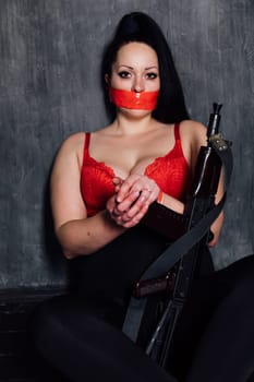 brunette woman with her mouth closed in a dark room with a gun