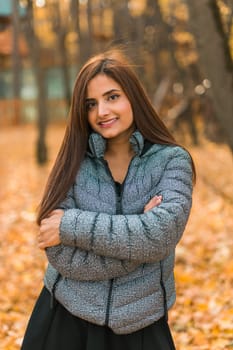 Close-up portrait of a young beautiful confident Indian Asian woman in fall outdoor. Happy and natural smiling female. Generation z and gen z youth