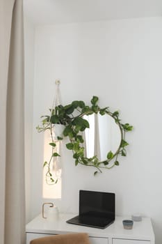 cozy workplace with a laptop on the table and a flower by the round mirror. home interior decoration