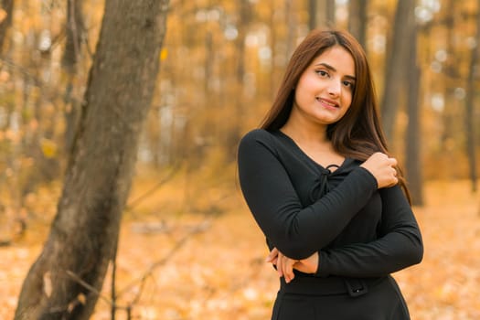 Close-up portrait of a young beautiful confident Indian Asian woman in fall outdoor. Happy and natural smiling female. Generation z and gen z youth