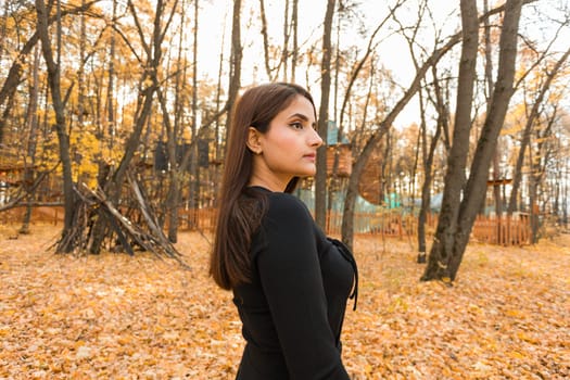 Close-up portrait of a young beautiful confident Indian Asian woman in fall outdoor. Happy and natural smiling female. Generation z and gen z youth