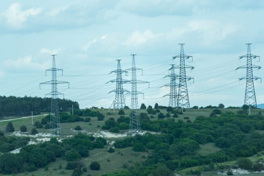 High voltage towers with sky background. Power line support with wires for electricity transmission. High voltage grid tower with wire cable at distribution station. Energy industry, energy saving.