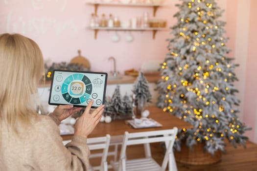 Modern home smart automation app on tablet display in woman hands at Christmas.