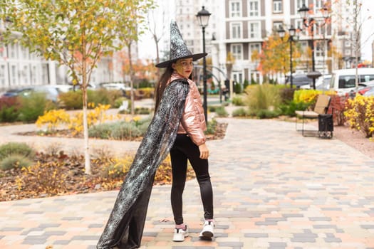 caucasian teenage girl in traditional witch or wizard hat, halloween outside costume, fancy dress party.