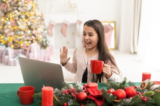 Happy girl using laptop at home during christmas.