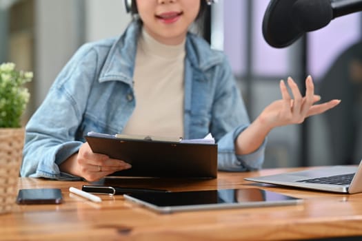 Female radio host discussing various topics with her guest while streaming live audio podcast from home studio.