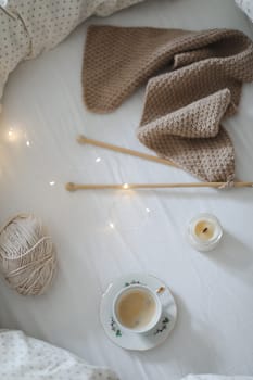 yarn and a cup of coffee on the bed. Hygge lifestyle, cozy mood. Handicraft day concept.