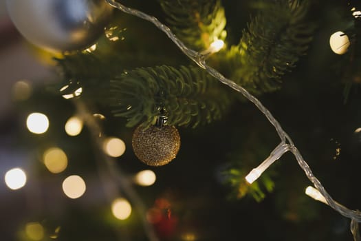 Christmas and New years eve Background. Close up of balls on christmas tree. Bokeh garlands in the background. New Year concept. Decorated Christmas tree on blurred, sparkling and fairy background