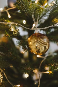 Christmas and New years eve Background. Close up of balls on christmas tree. Bokeh garlands in the background. New Year concept. Decorated Christmas tree on blurred, sparkling and fairy background