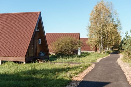 The concept of glamping and renting a chalet for weekend. Wooden house with a veranda in nature around coniferous trees.