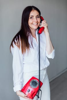 brunette woman talking on wired phone and smiling