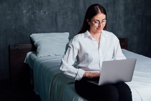 Woman working with laptop in bedroom