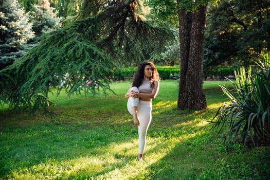 Young asian woman practicing yoga during workout in park