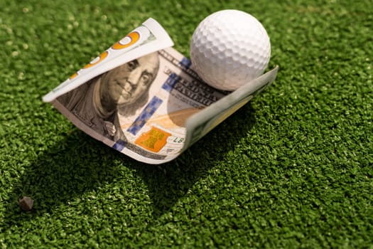 Money, mini golf balls on grass. Concept of sports bet.