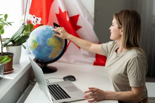 female student sitting with canadian flag and using laptop . High quality photo
