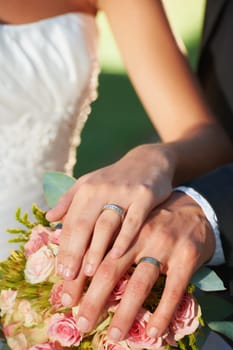 Couple, wedding ring and hands in marriage with rose bouquet at celebration and trust event. Flower, loyalty and care with romance and groom jewelry with love and commitment with woman and man.