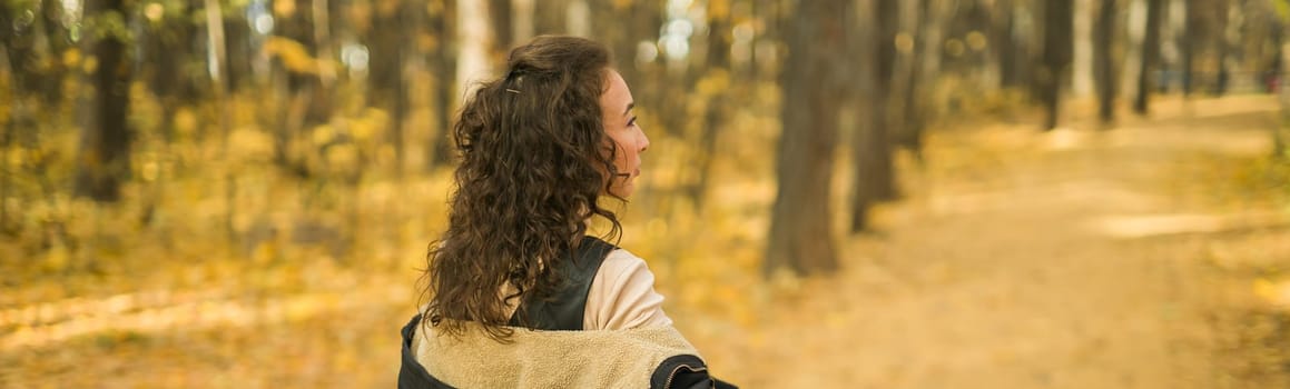 Autumn portrait of a beautiful happy curly woman in fall season. Millennial generation female. Natural beauty