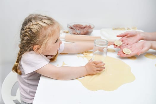 Girl helping mother on the kitchen to make dumplings