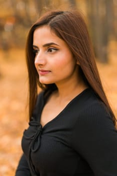 Close up portrait of pretty indian young woman enjoying warm autumn sunny day vacation outdoors. Generation z and gen z concept. Fall Season.