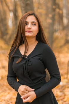 Close up portrait of pretty indian young woman enjoying warm autumn sunny day vacation outdoors. Generation z and gen z concept. Fall Season.