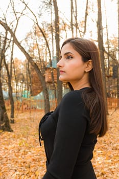 Close up portrait of pretty indian young woman enjoying warm autumn sunny day vacation outdoors. Generation z and gen z concept. Fall Season.