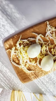 Chopped Peking cabbage and peeled eggs on cutting board as background. Cooking a healthy eco-friendly salad from natural products. Copy space and place for text