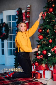 woman at christmas tree with gifts for new year