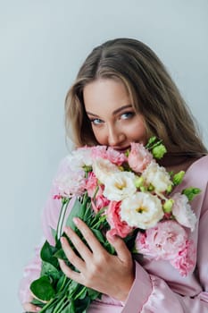 Portrait of a delicate woman in a pink dress with a bouquet of flowers