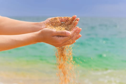 Young woman with sand in her hands. Yellow sand crumbles into and through a woman's hands.
