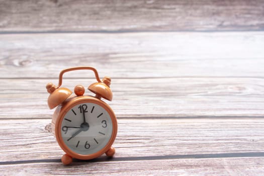 Orange alarm clock isolated on wooden desk. The clock set at 8 o'clock. Copy space.