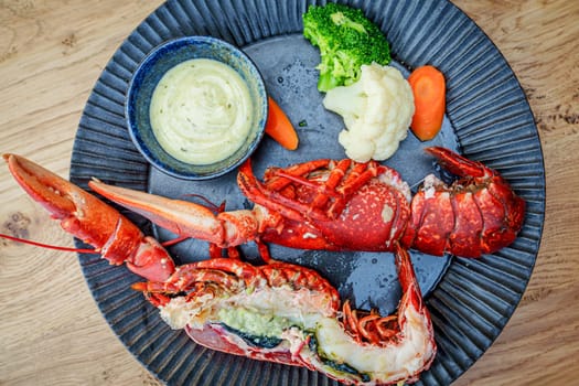 A close-up of deliciously boiled red lobster halves served on a stylish black plate at a fine dining restaurant. The succulent lobster meat is perfectly cooked and ready to be enjoyed.