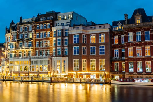 Beautiful long exposure shot capturing the mesmerizing view of Amsterdam canals at night, with the city lights reflecting on the calm waters, creating a surreal and captivating scene.