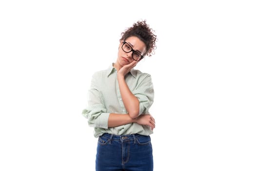 young tired woman student with curly hair in a shirt on a white background.