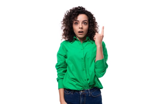 young surprised european brunette woman with curly hair in a green shirt wants to tell interesting news. advertising concept.
