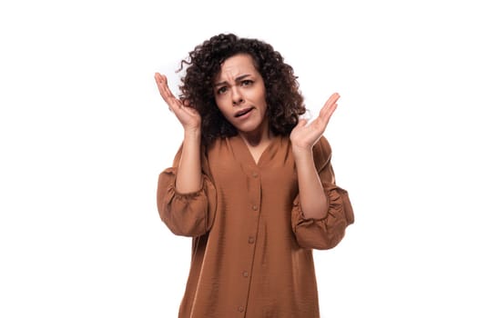 young emotional curly leader woman in a brown shirt on a white background.