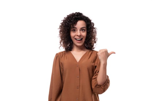 young surprised caucasian curly brunette woman dressed in a stylish brown blouse on a white background.