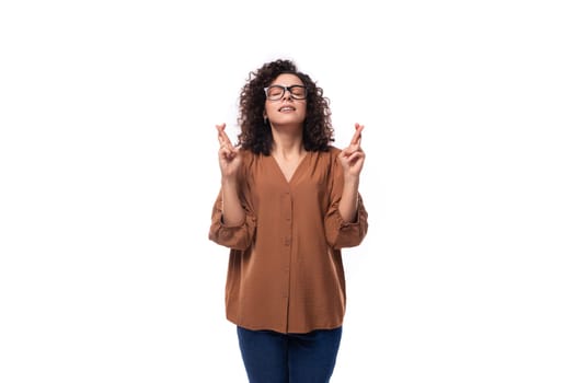 young smart slim woman with curly haircut dressed in brown blouse crossed her fingers.