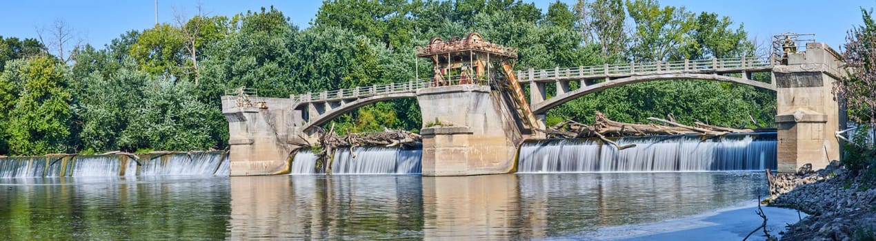Image of Maumee River Dam Fort Wayne, IN panorama on bright and sunny summer day with logs over waterfalls