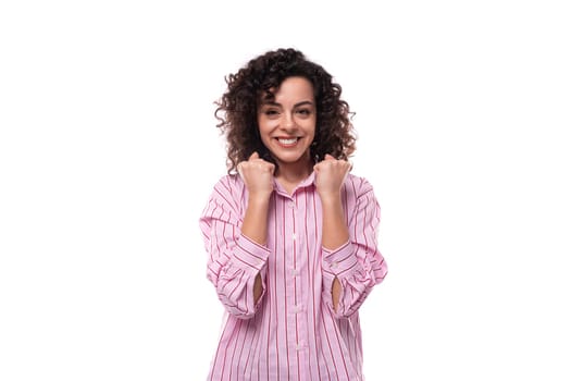 portrait of a 30 year old stylish slim curly brunette model woman dressed in a shirt with a striped print.