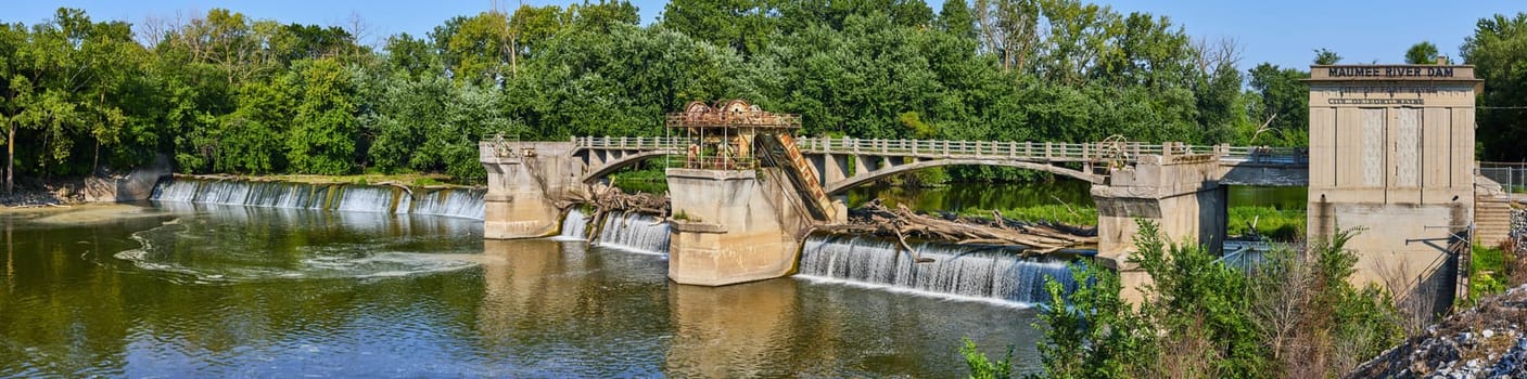 Image of Maumee River Dam panorama of logs clogging waterfall and forest background in Fort Wayne, IN