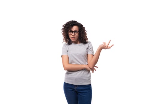smart young curly brunette woman with glasses for vision in a gray t-shirt on a white background with copy space.