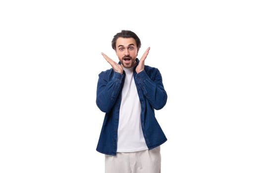 handsome young brunette man in a denim shirt gesturing with his hands on a white background.