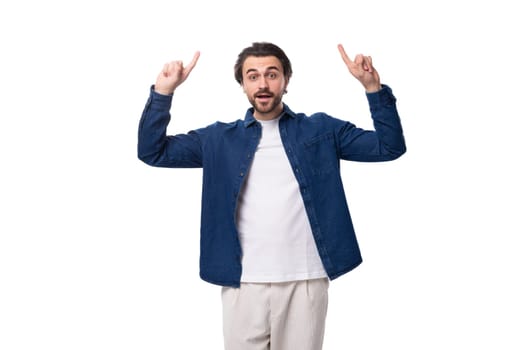 handsome well-groomed young brunette man in a denim shirt wants to tell interesting news.