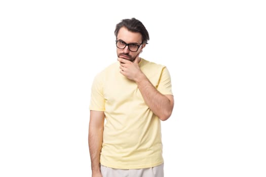 young smart brunette man in a t-shirt and glasses on a white background with copy space.