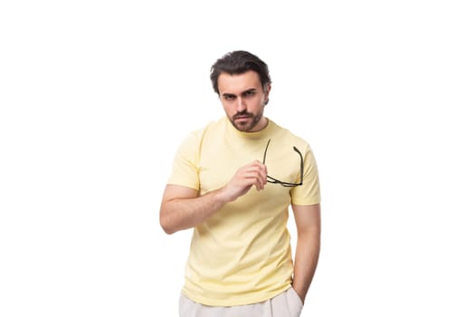 handsome young brunette man with a beard put on glasses for vision correction.