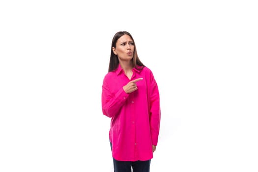 portrait of a smart young lady with black hair in a crimson shirt who is thoughtful and looks at the empty space.