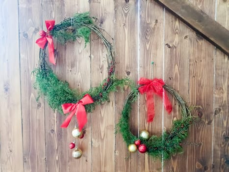 Christmas wreath with red and gold bauble decorations, bow, holly, mistletoe, pine cones and blue spruce fir over dark wood front door background.