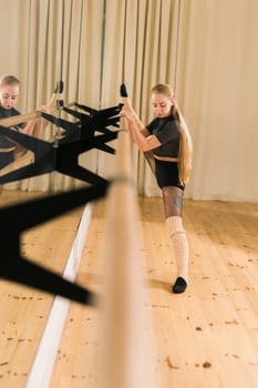 Female ballet dancer practicing at barre in dance studio - dance and ballerina