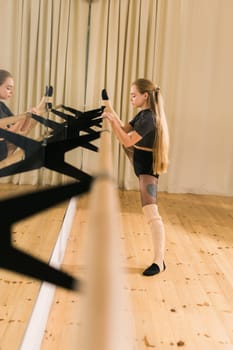 Female ballet dancer practicing at barre in dance studio - dance and ballerina