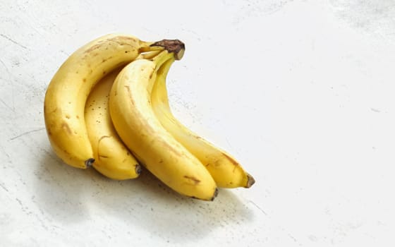 Bunch of ripe bananas on white working board.